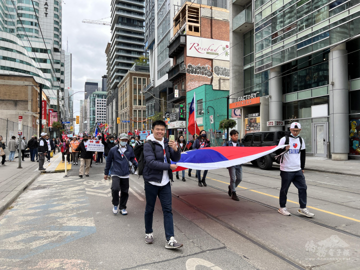 6位參與搭僑計劃活動的安省多倫多及倫敦地區留學生們抬著中華民國國旗參與「多倫多全僑慶祝111年雙十國慶大會暨遊行活動」
