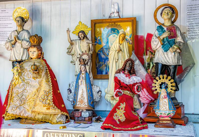 There are several different religious icons in the shrine outside St. Christopher Church, including the Black Nazarene, which is popular in the Philippines, the Baby Jesus, the resurrected Jesus, and the Virgin Mary dressed in blue and white.