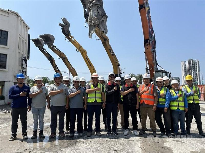 Workers and excavators line up Wednesday facing the direction of the demolished Uranus building to pay tribute to a woman surnamed Kang (康), a resident of the building who died attempting to save her cat in the April 3 earthquake. CNA photo
