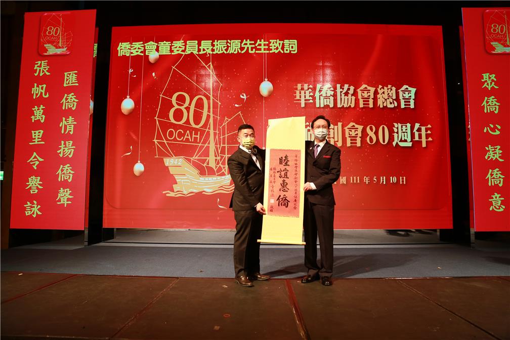 華僑協會總會舉辦「慶祝創會八十週年慶祝大會」，僑務委員會童委員長振源(右)致贈「睦誼惠僑」賀軸。