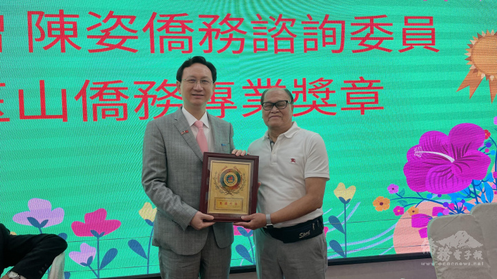 童振源(左)頒贈伍煥鵬(右)惠國利僑獎牌，表彰長期貢獻