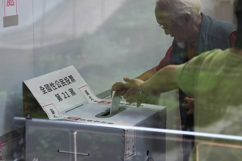 A voter casts a ballot with the guidance of an election staffer at Taipei Municipal Tianmu Elementary School on Saturday. CNA photo Aug. 23, 2025