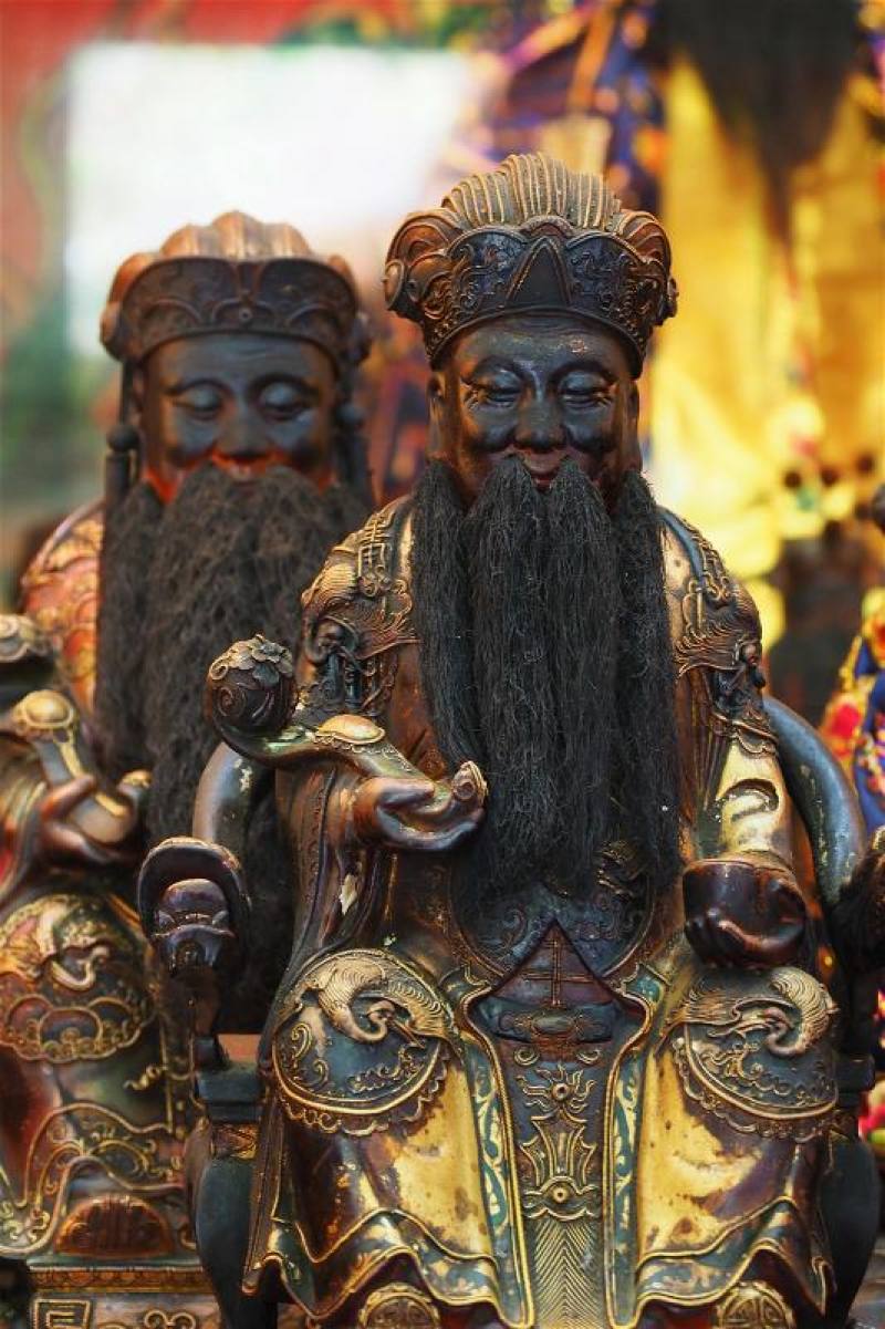 Earth God icons in cities hold gold ingots, symbolizing wealth