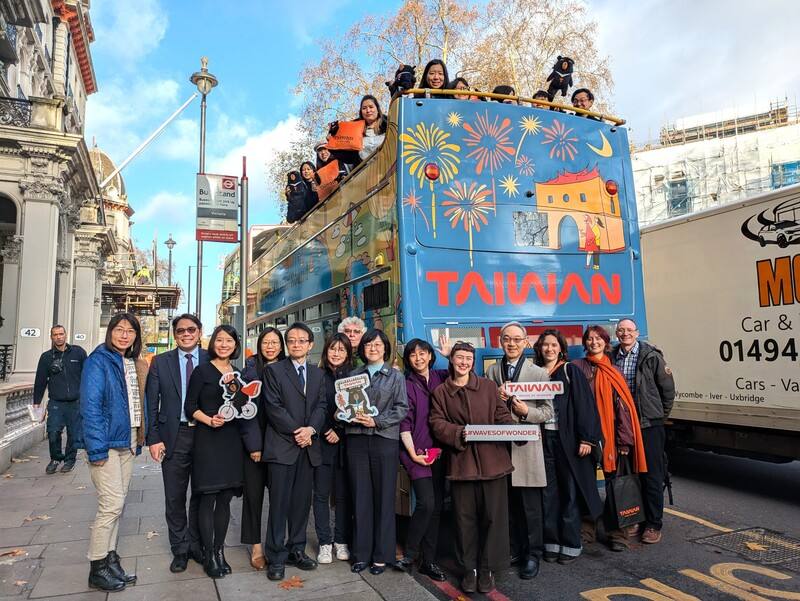 British illustrator Hannah Gibson (fifth from the right on the ground) and Taiwanese tourism officials pose for a photo with a sightseeing bus covered in Gibson's Taiwan-themed illustrations in London, the United Kingdom, on Friday. CNA photo Dec. 13, 202