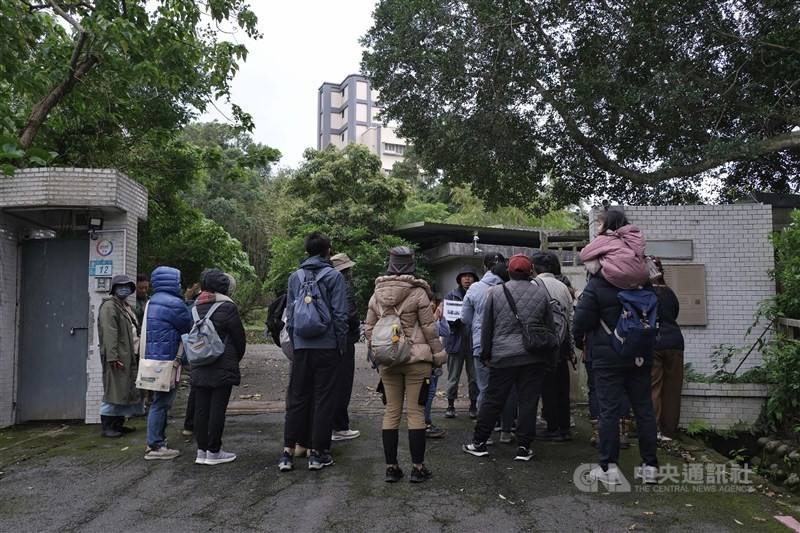Visitors listen to a tour guide in front of the gate of the Ankang Reception House. CNA photo Feb. 12, 2026